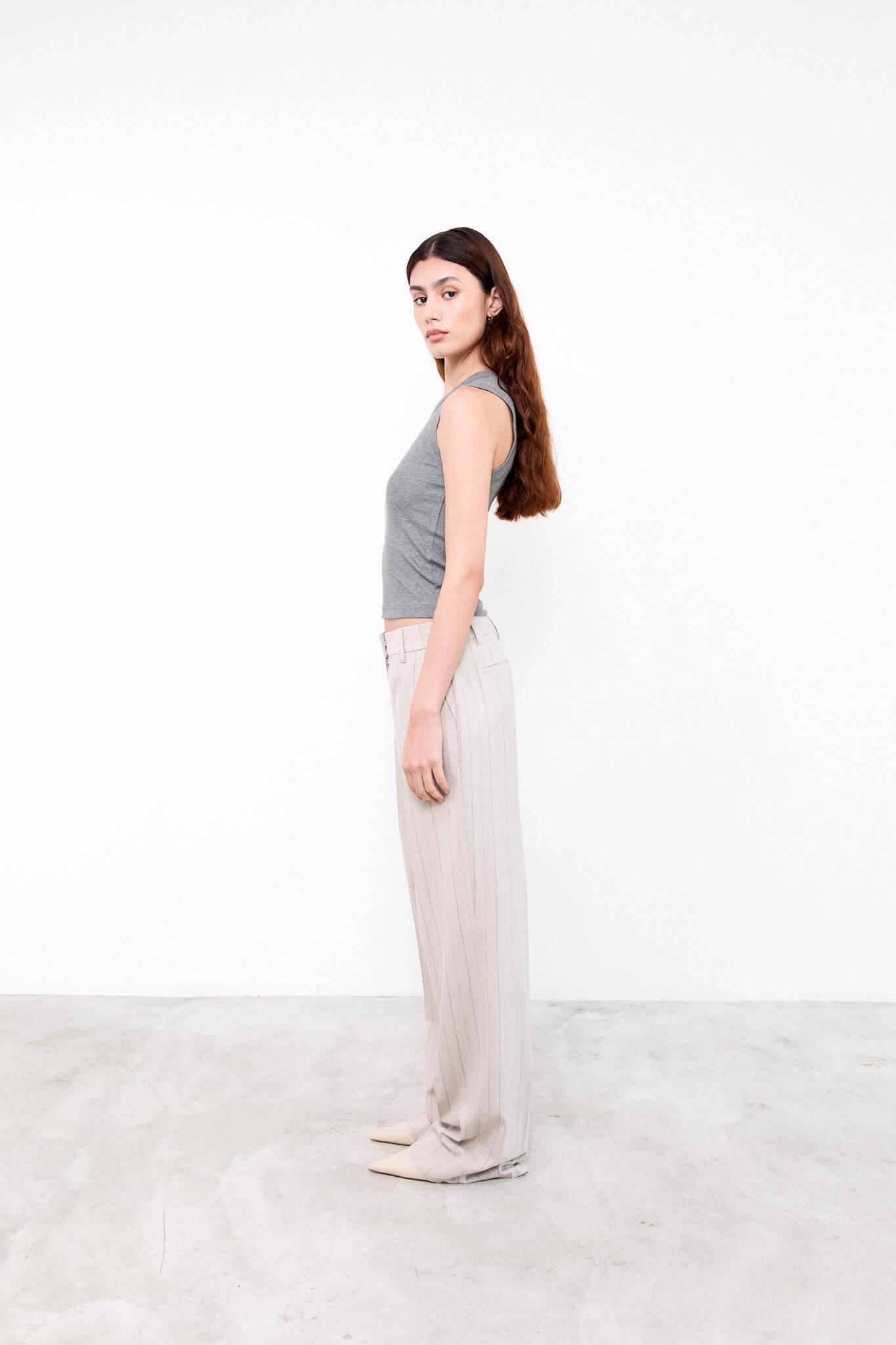 Woman wearing a gray sleeveless top and beige pants