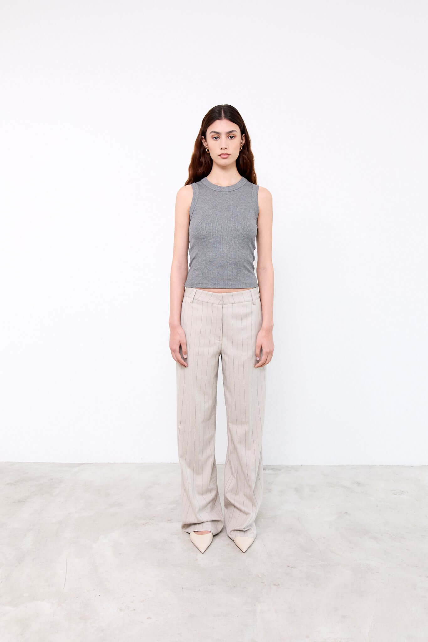 Woman wearing a gray sleeveless top and beige pants