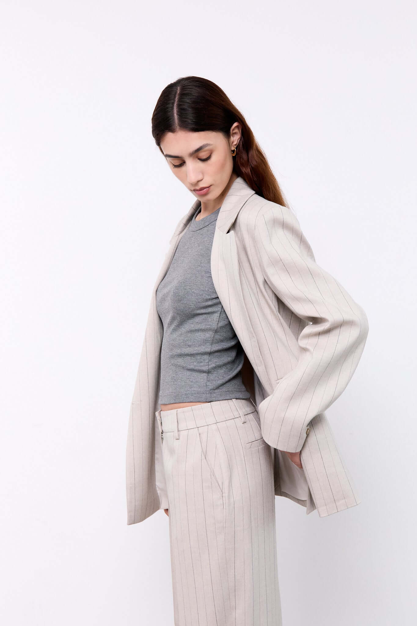 Woman wearing a light gray blazer over a gray top and white pants