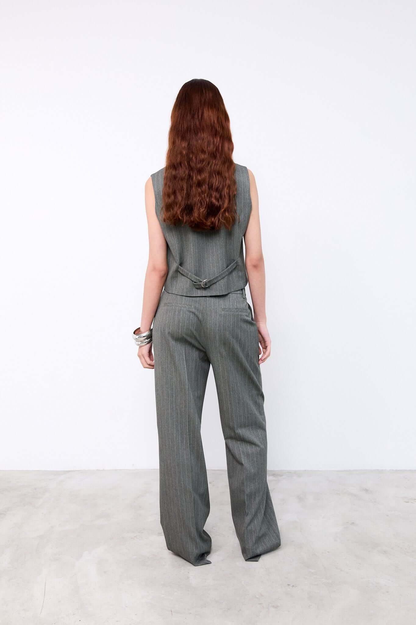 Person wearing a gray sleeveless top and high-waisted pants