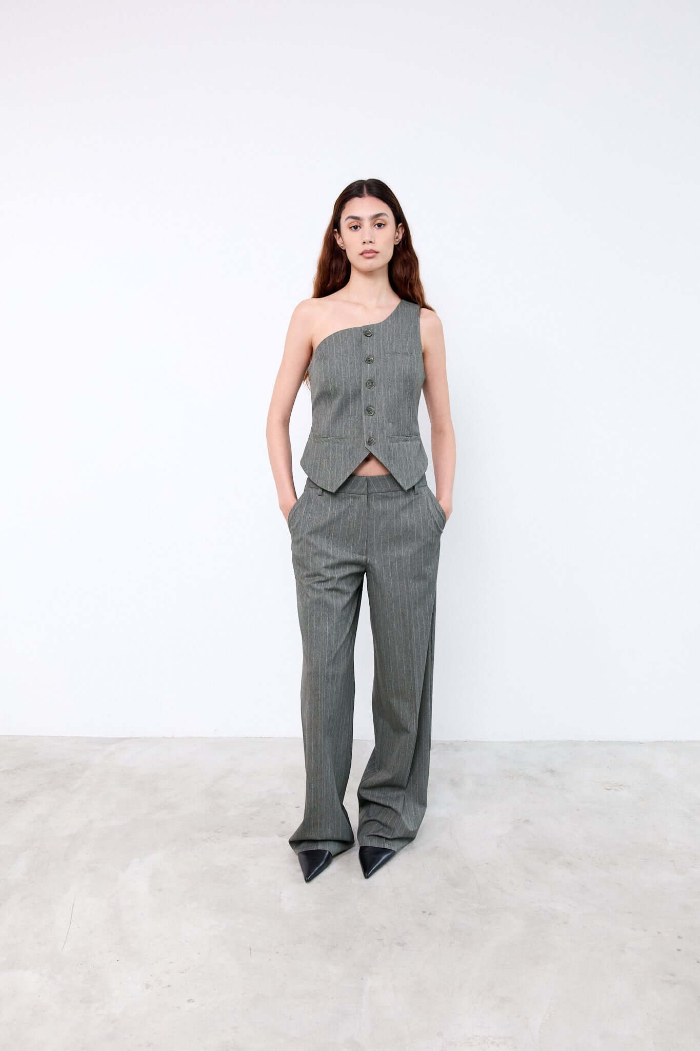 Woman wearing a gray one-shoulder top and high-waisted pants