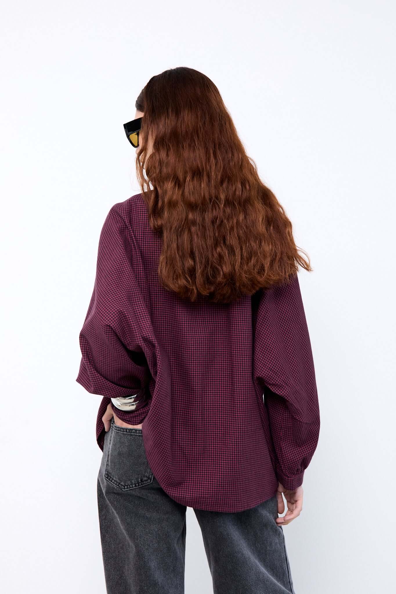 Person wearing a loose-fitting burgundy shirt and dark jeans