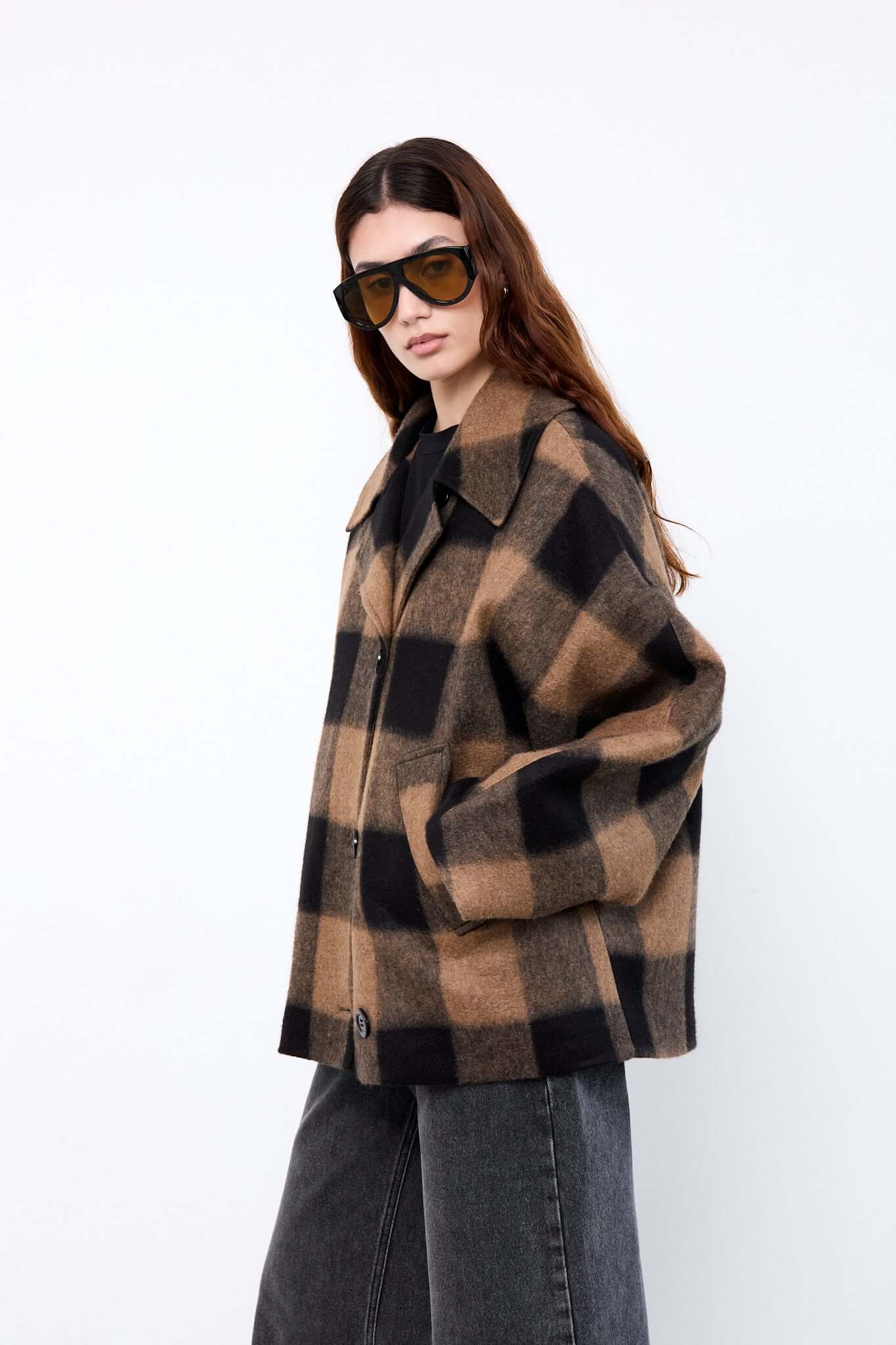 Woman wearing a plaid coat and sunglasses