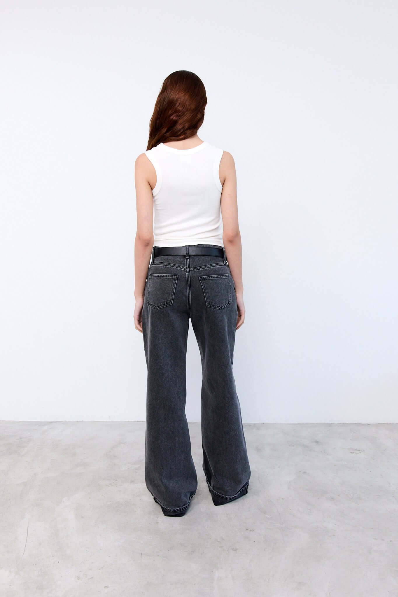 Person wearing a white sleeveless top and dark jeans