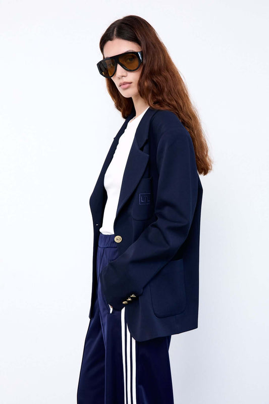 Person wearing a navy blazer, white shirt, and blue pants with white stripes