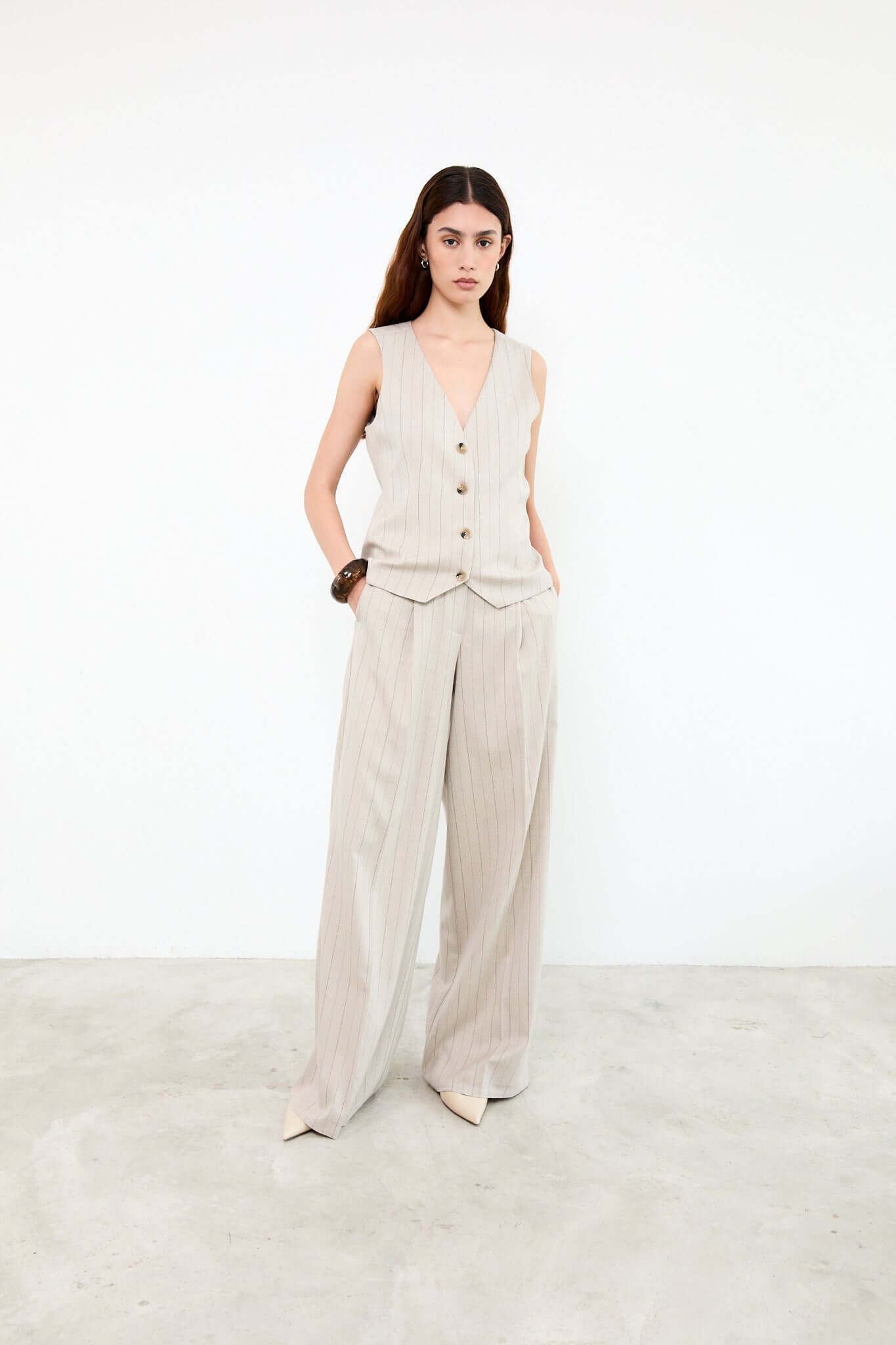 Woman wearing a beige sleeveless top and wide-leg pants