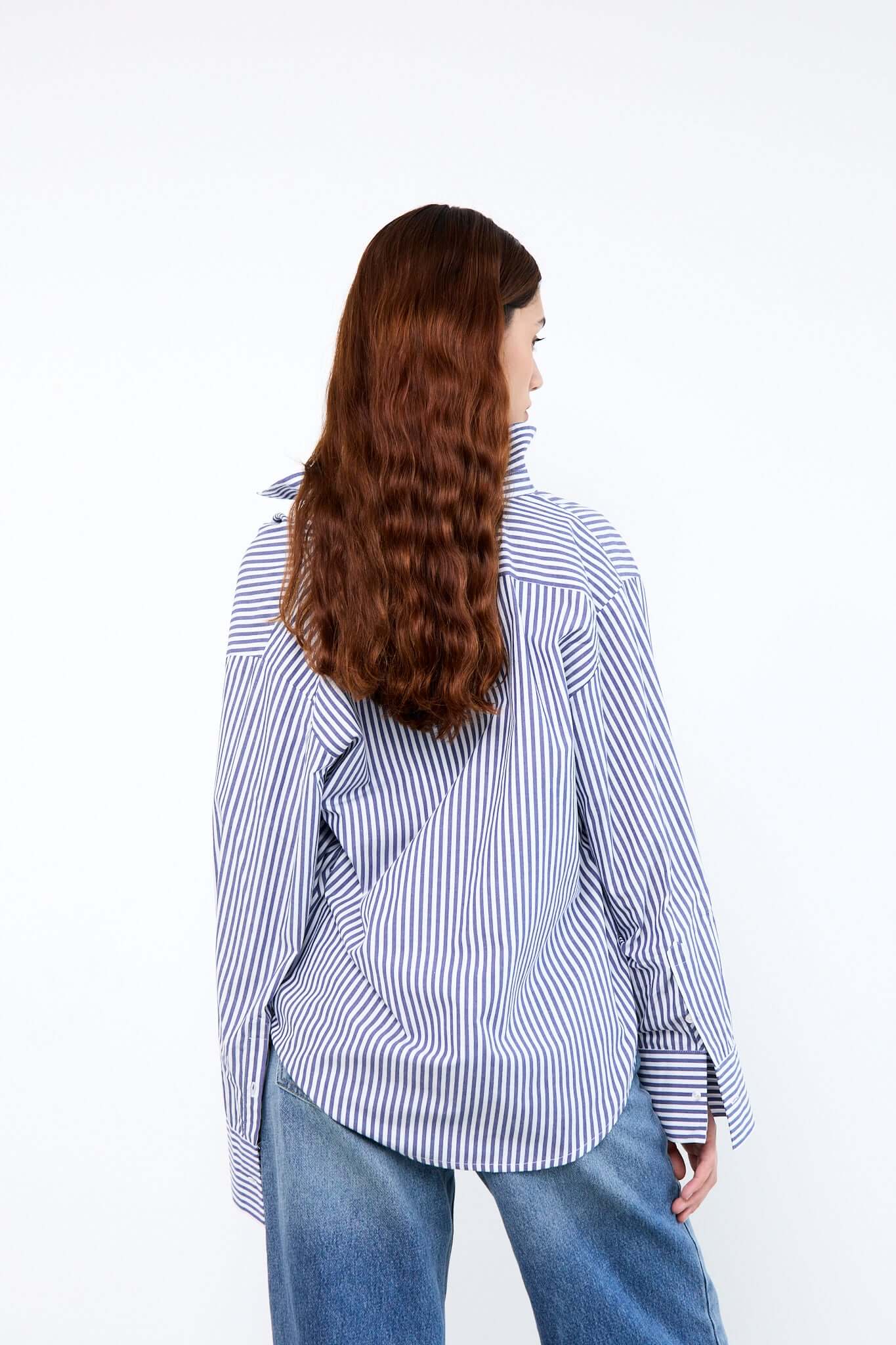 Person wearing a blue and white striped shirt and jeans from behind