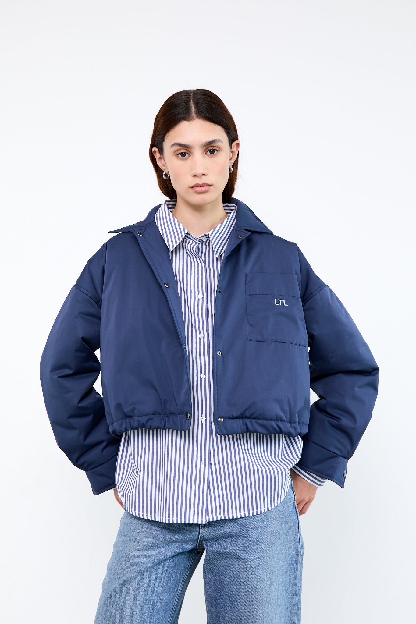 Person wearing a blue jacket over a striped shirt