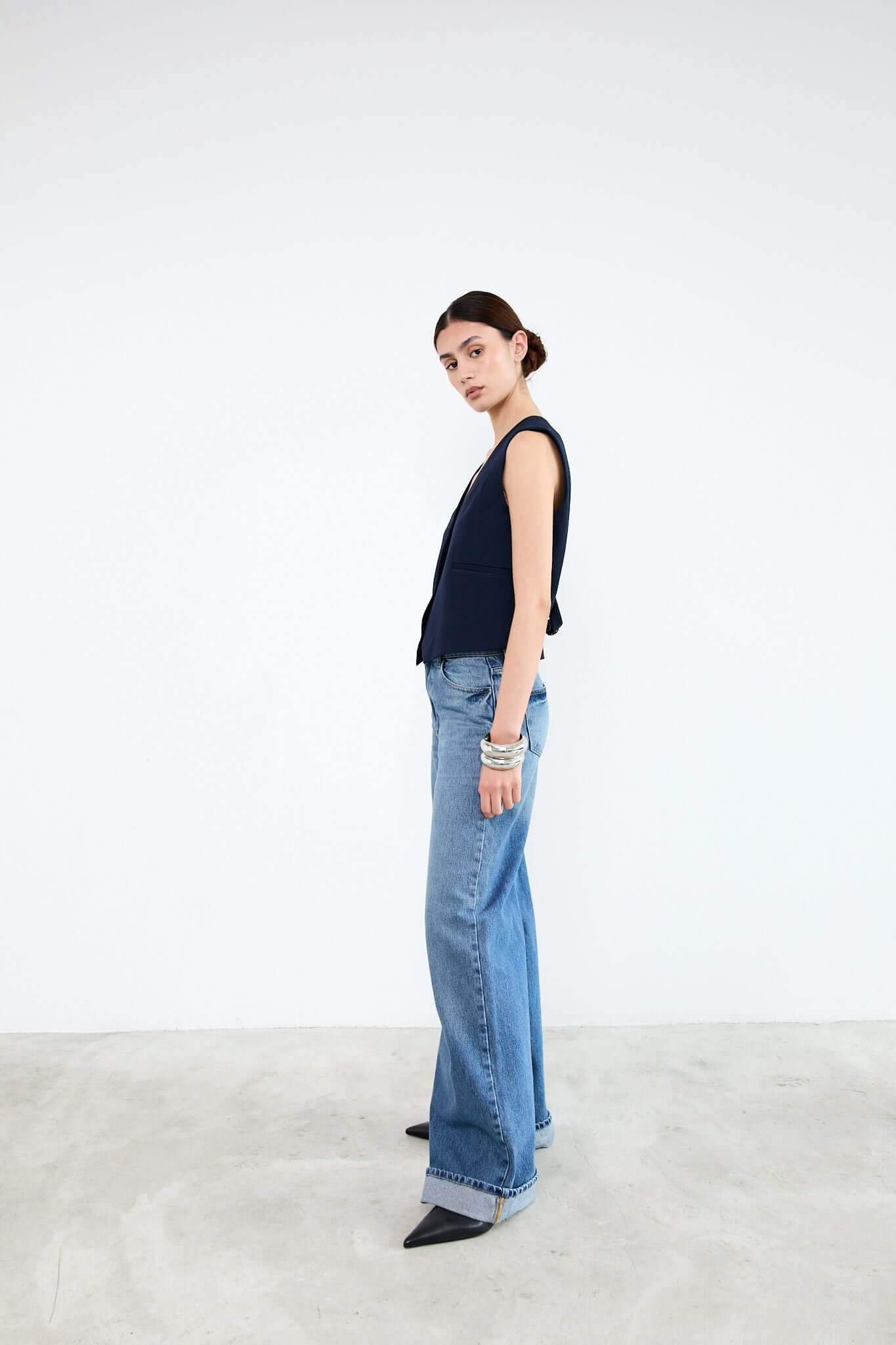 Woman wearing a navy sleeveless top and light blue jeans