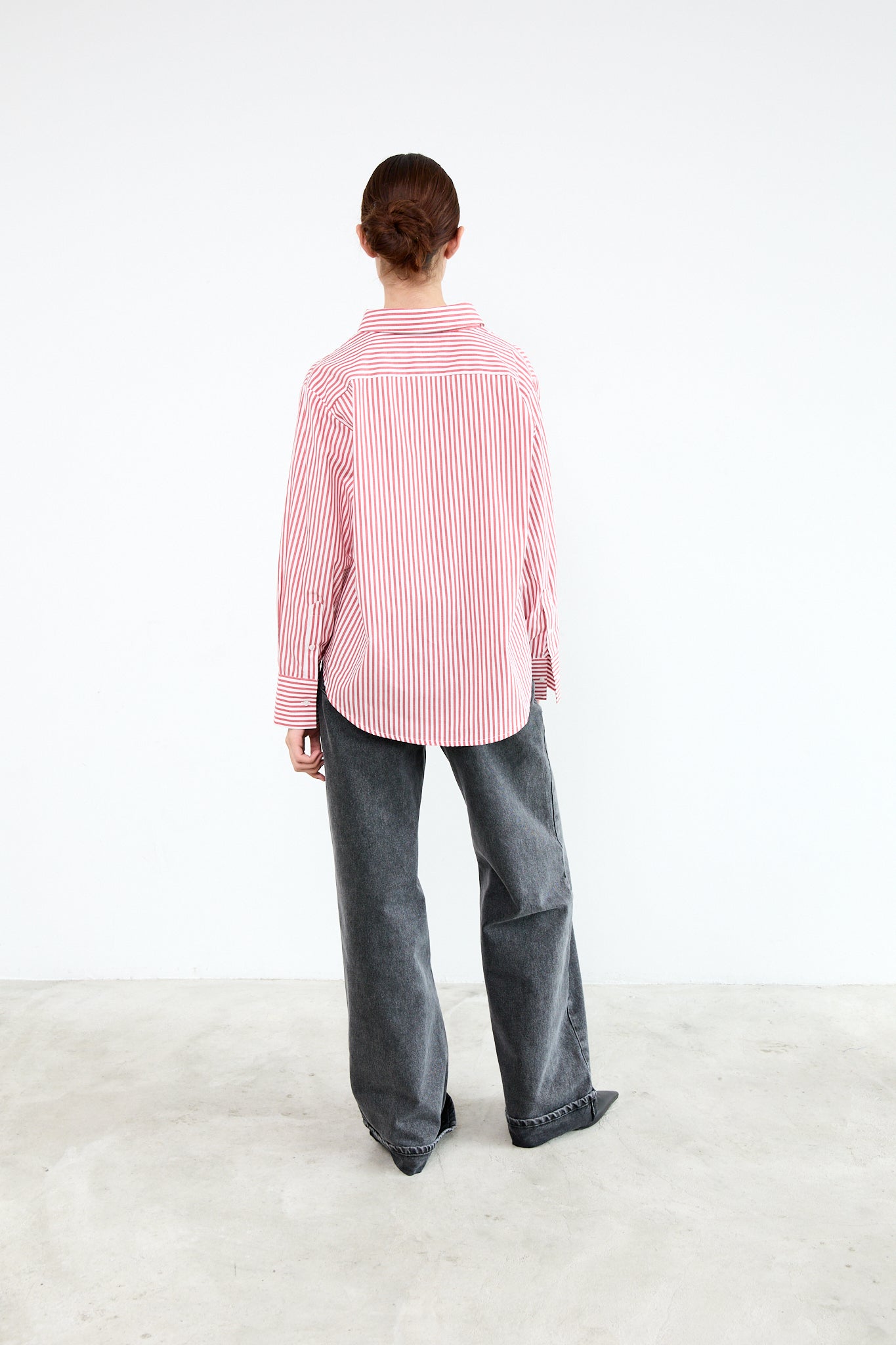 Person wearing a pink and white striped shirt and gray pants