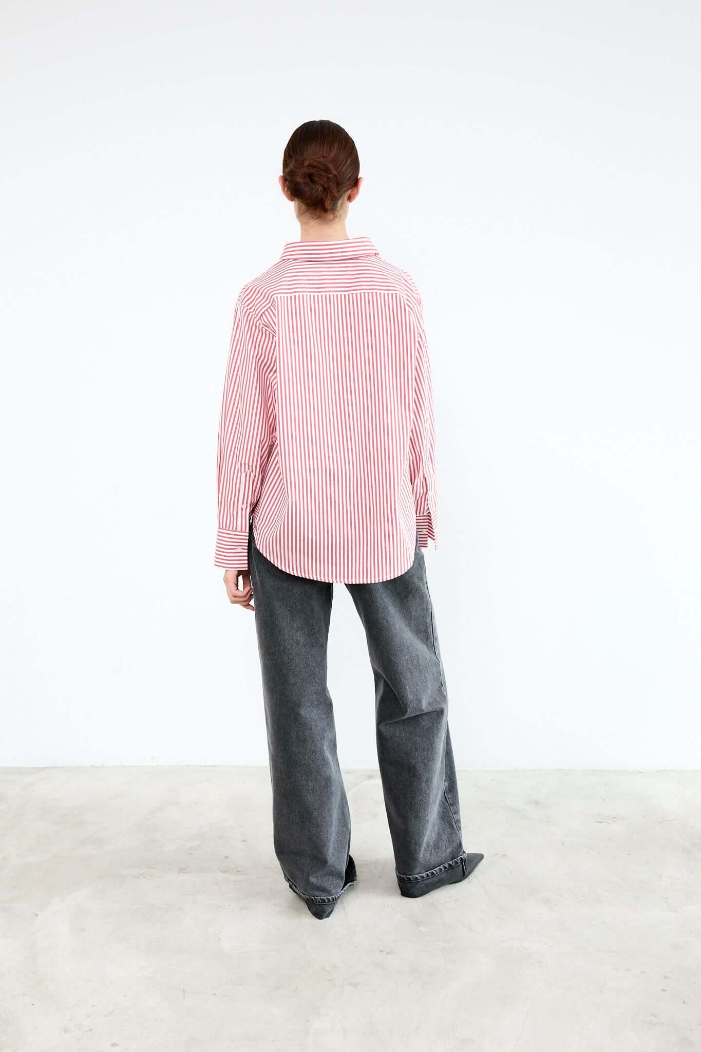 Person wearing a pink and white striped shirt and gray pants