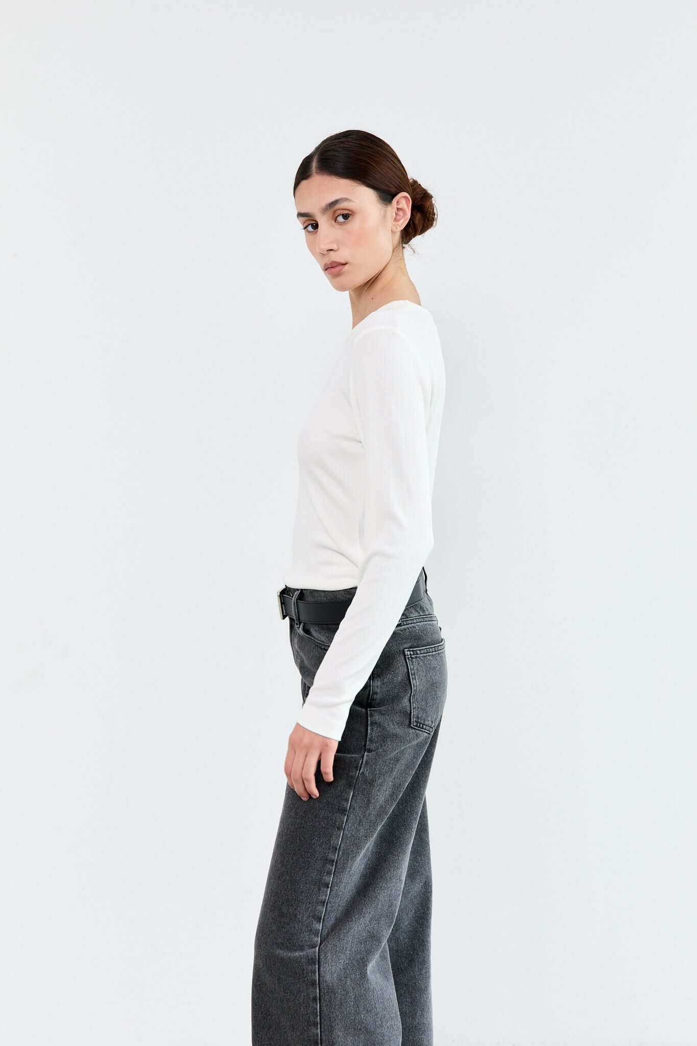 Woman wearing a white long-sleeve shirt and gray jeans