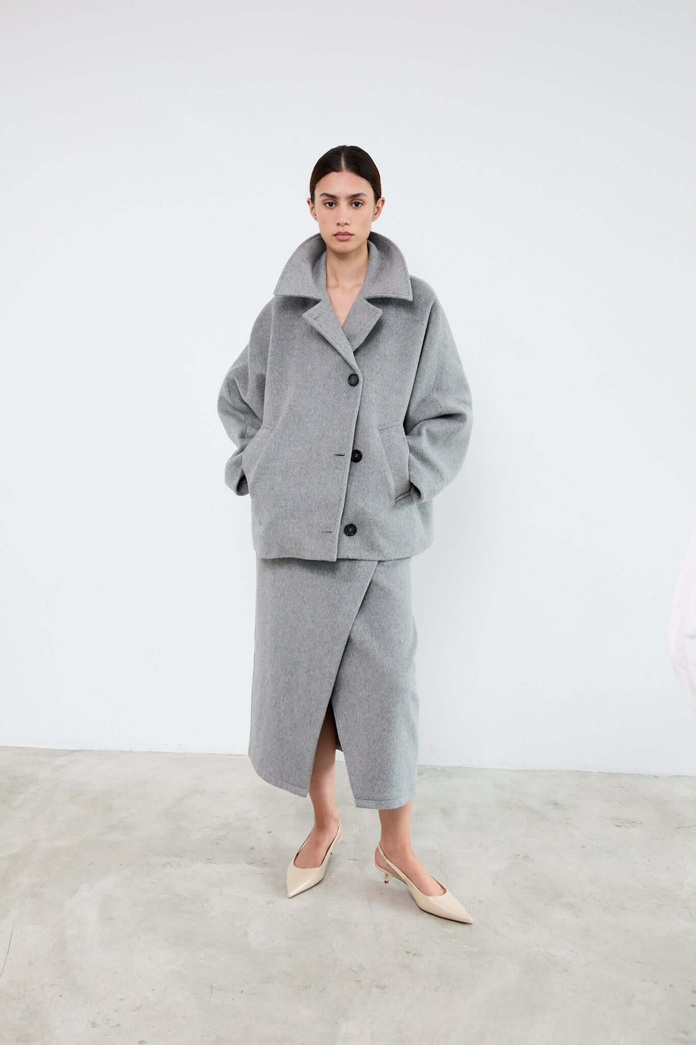 Woman wearing a gray coat and skirt