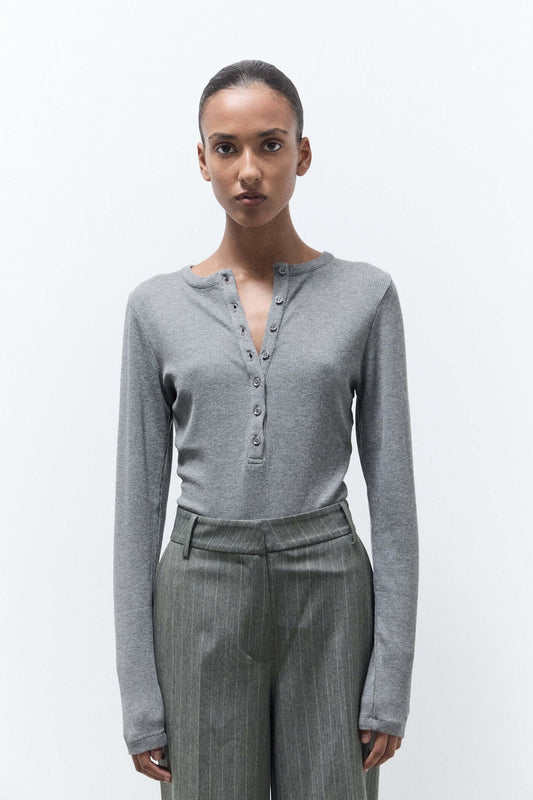 Woman wearing a gray long-sleeve top and gray pants on a white background