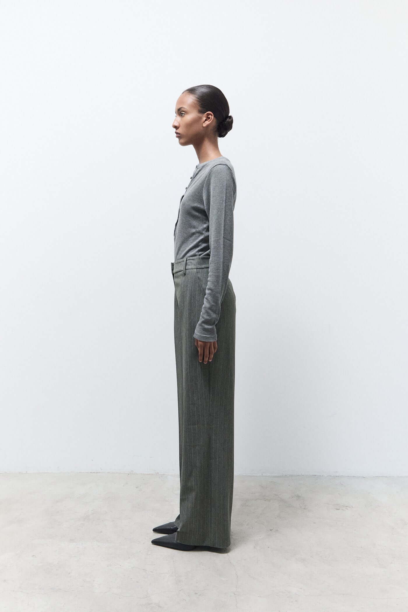 Person wearing a gray outfit standing against a white background