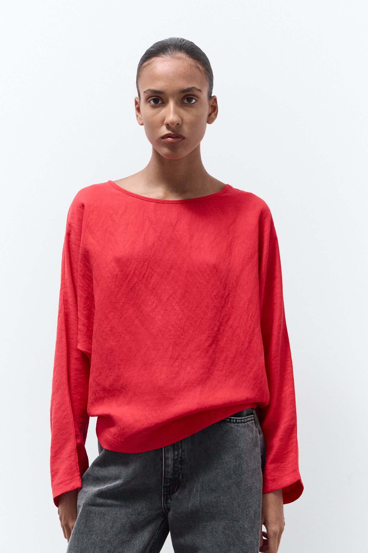 Person wearing a red sweater and gray pants on a white background