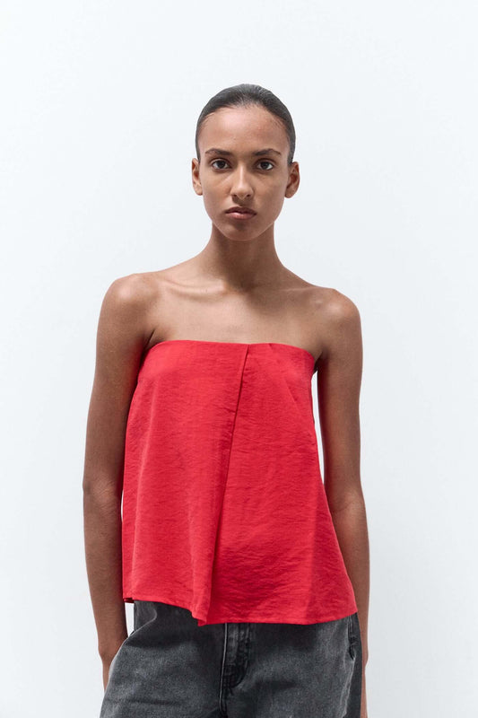 Woman wearing a red strapless top and gray pants on a white background