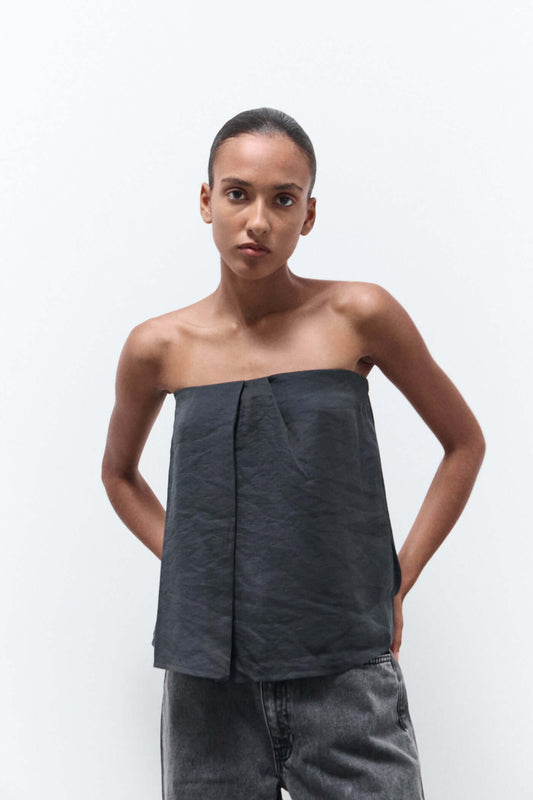 Woman wearing a strapless dark gray top and jeans on a white background