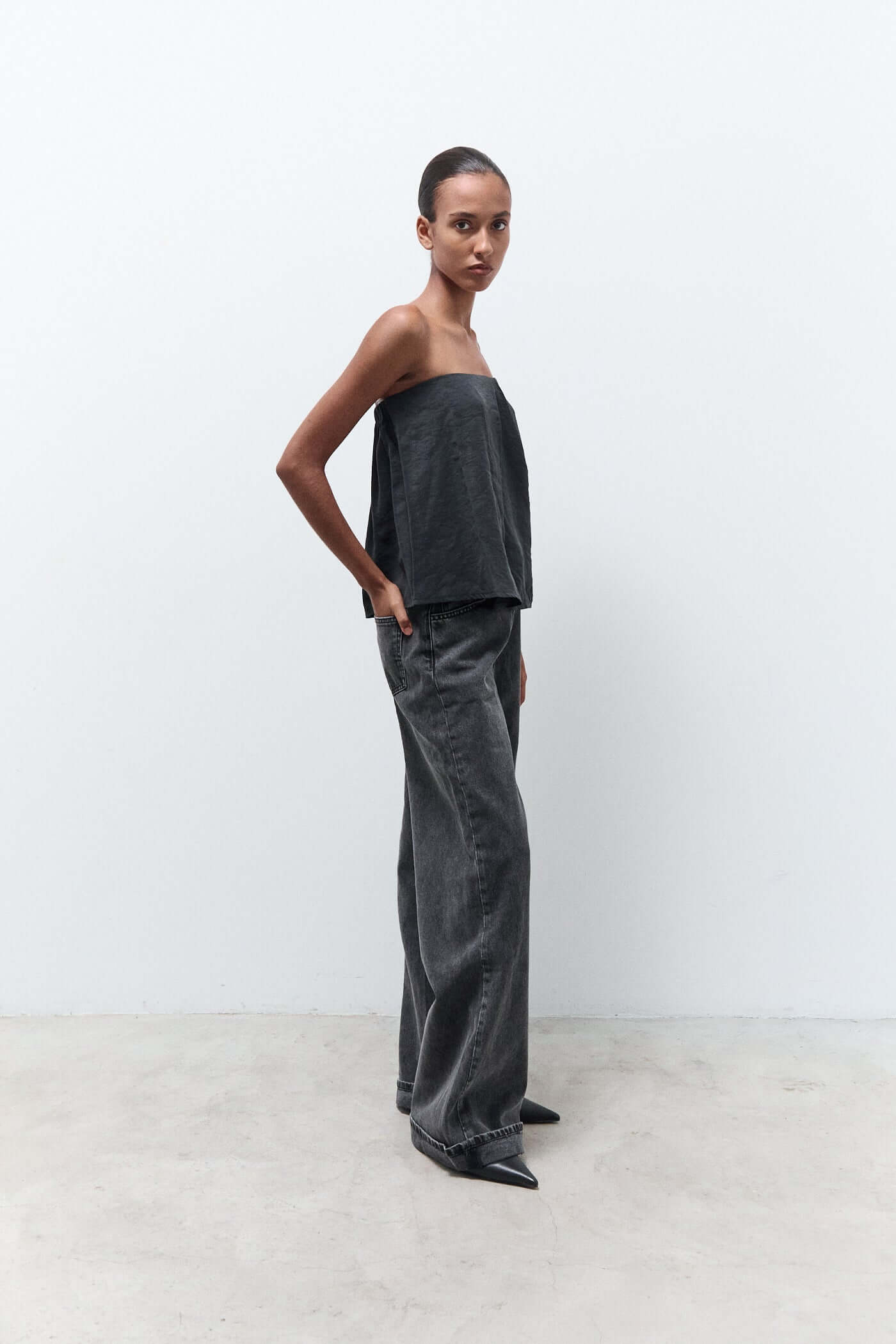Woman wearing a strapless top and wide-leg pants against a white background