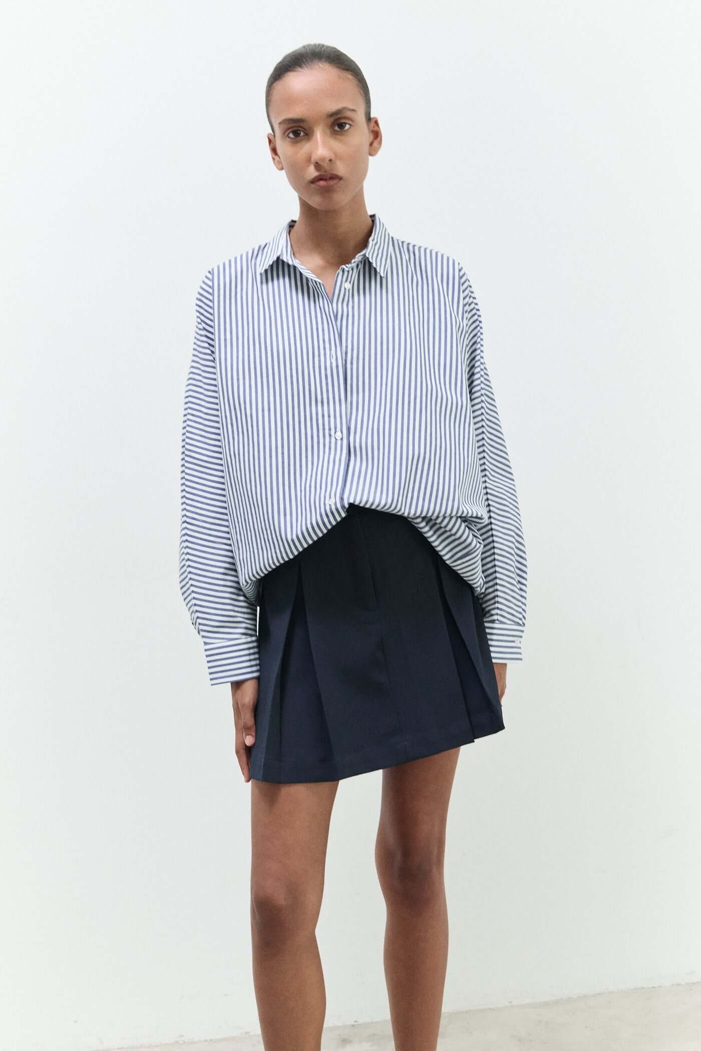 Person wearing a striped shirt and navy skirt