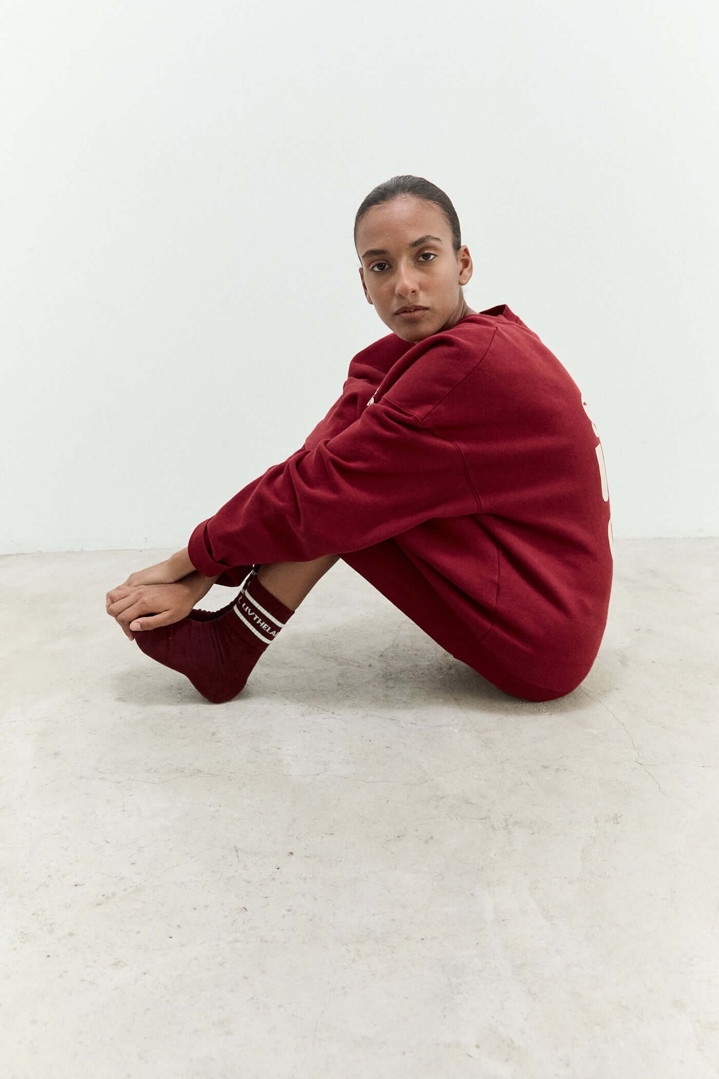 Person wearing a red outfit sitting on a white floor.