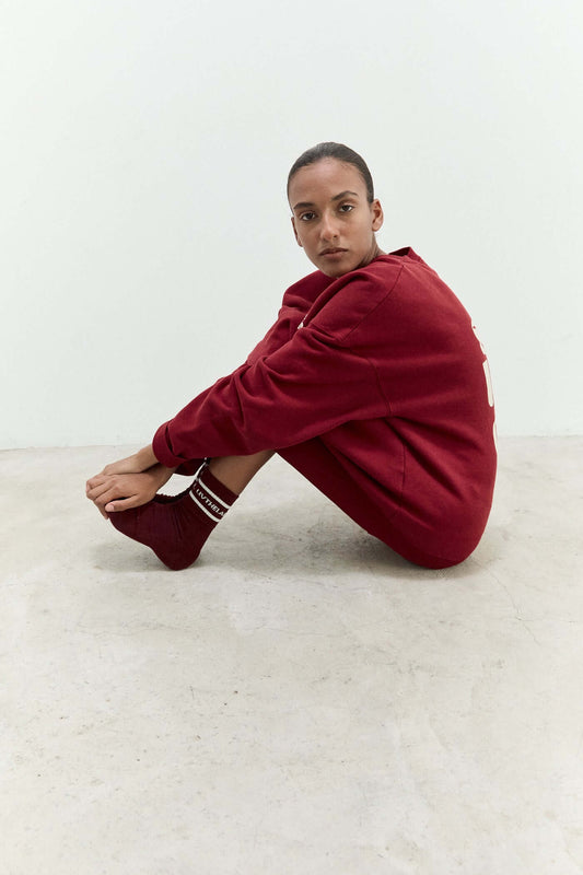 Person wearing a red outfit sitting on a white floor.