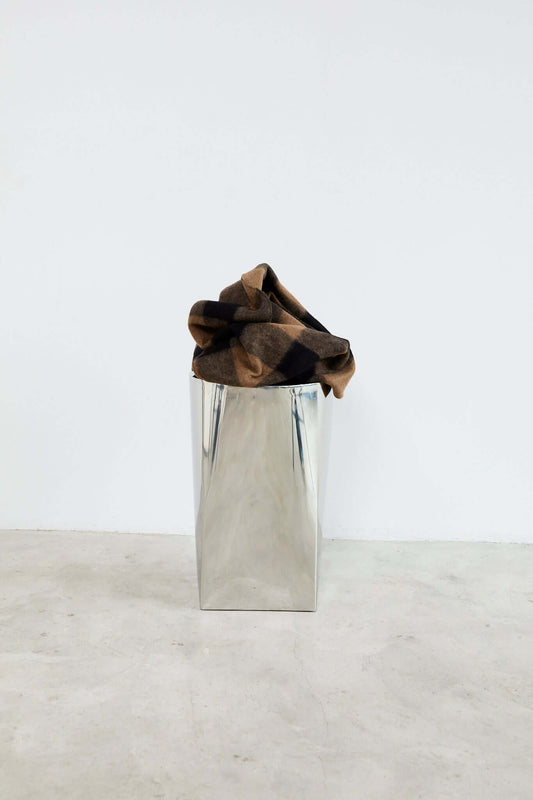 Brown fabric folded on top of a metallic vase