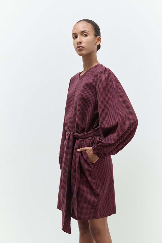 Woman wearing a burgundy textured dress on a white background