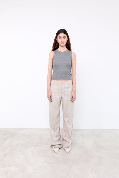 Woman wearing a gray sleeveless top and beige pants 