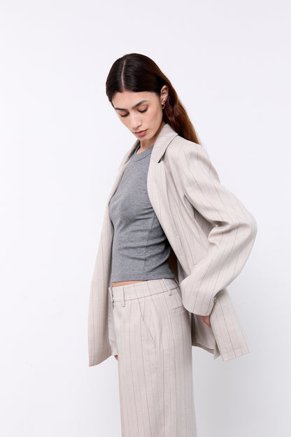 Woman wearing a light gray blazer over a gray top and white pants 