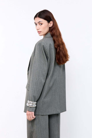 Woman wearing a gray suit with silver cuffs