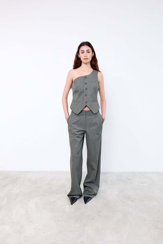 Woman wearing a gray one-shoulder top and high-waisted pants