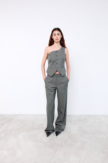 Woman wearing a gray one-shoulder top and high-waisted pants