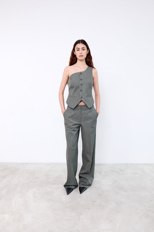 Woman wearing a gray one-shoulder top and high-waisted pants
