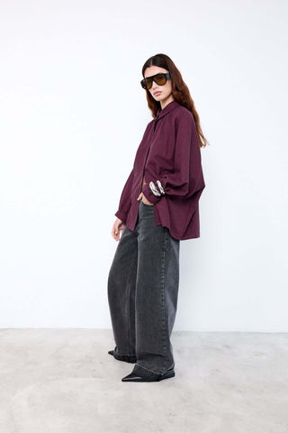 Person wearing a burgundy shirt and black jeans