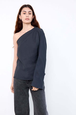 Woman wearing a dark gray one-shoulder top and jeans 