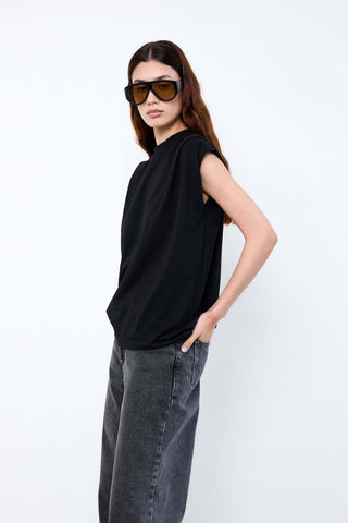 Woman wearing a black sleeveless top and gray pants