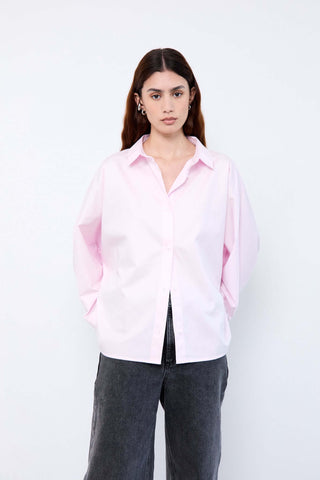 Woman wearing a light pink shirt and dark jeans
