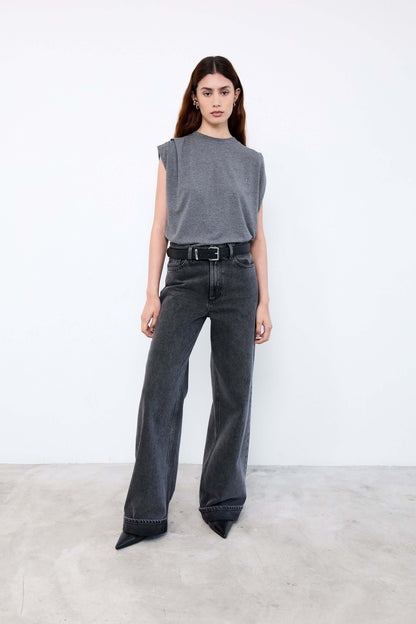 Woman wearing a gray sleeveless top and black jeans 