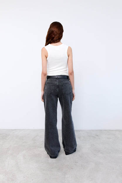 Person wearing a white sleeveless top and dark jeans