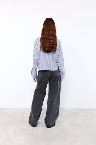 Person wearing a blue and white striped shirt and dark jeans