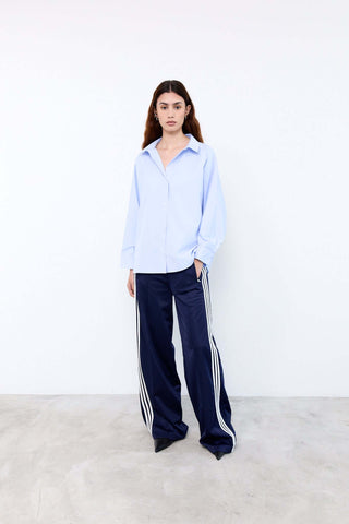 Person wearing a light blue shirt and navy pants with white stripes