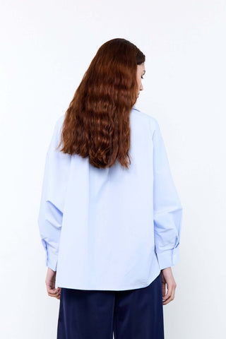 Person wearing a light blue shirt and dark pants 