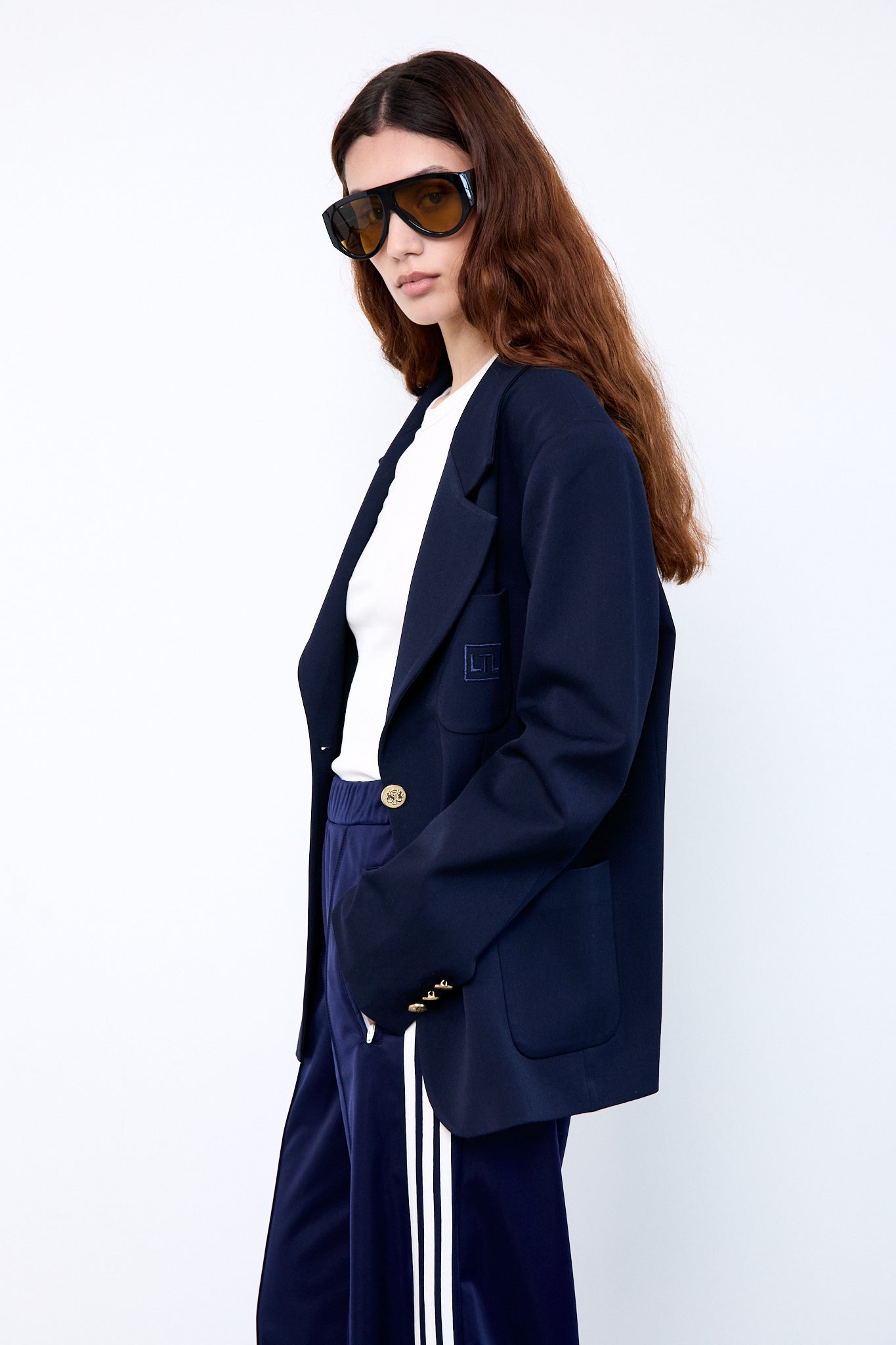 Person wearing a navy blazer, white shirt, and blue pants with white stripes 