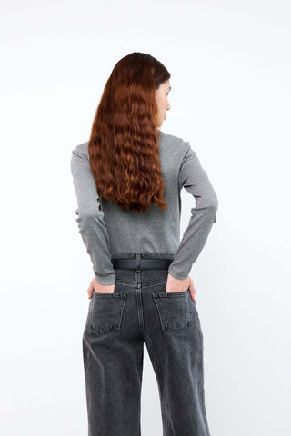 Person wearing a gray long-sleeve shirt and dark jeans