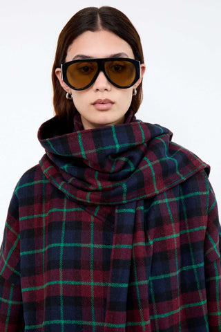 Person wearing a plaid coat and sunglasses 