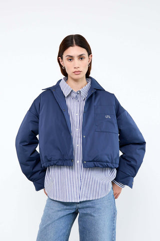 Person wearing a blue jacket over a striped shirt 