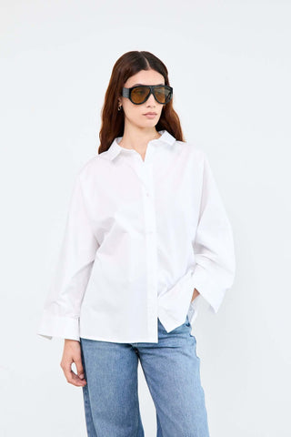 Woman wearing a white shirt and blue jeans with sunglasses on a white background