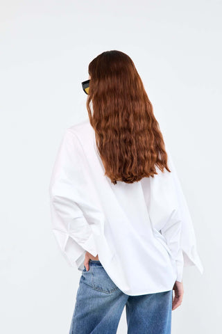 Person wearing a white oversized shirt and blue jeans on a white background