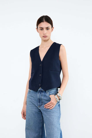 Woman wearing a navy vest and blue jeans